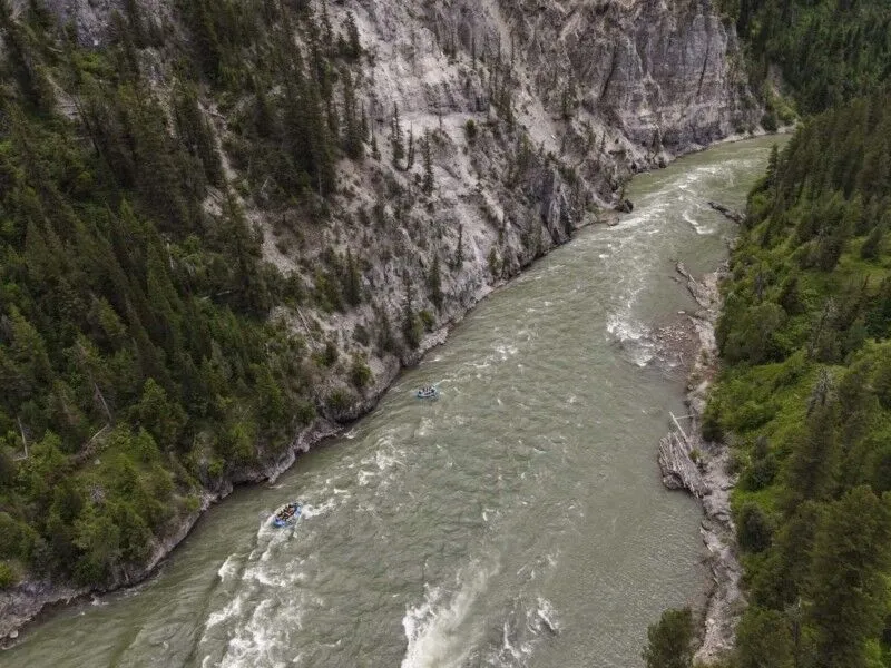 Two blue rafts navigate whitewater rapids as they float down the Snake River.