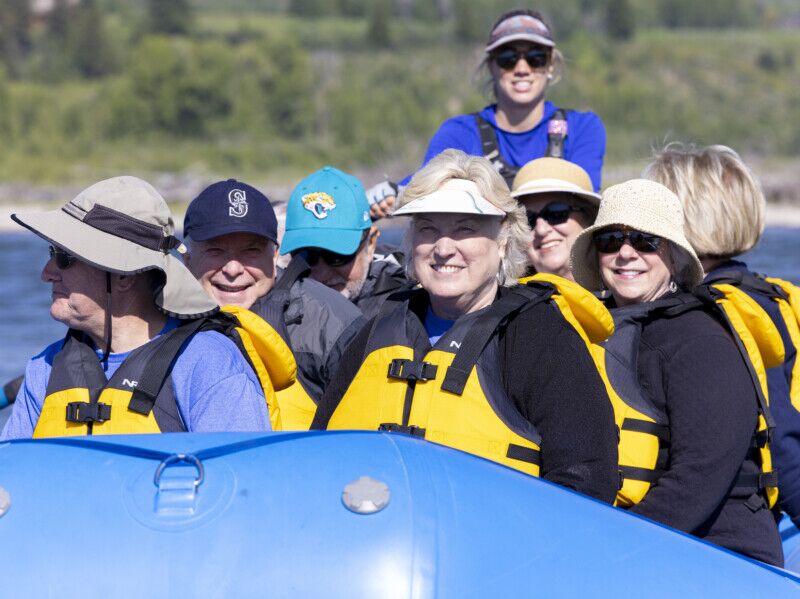 A group of older scenic rafting clients smile at the camera.