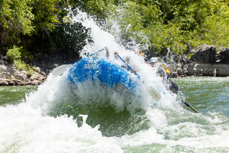 A blue Dave Hansen Whitewater splashes through a whitewater rapid on the Snake River.