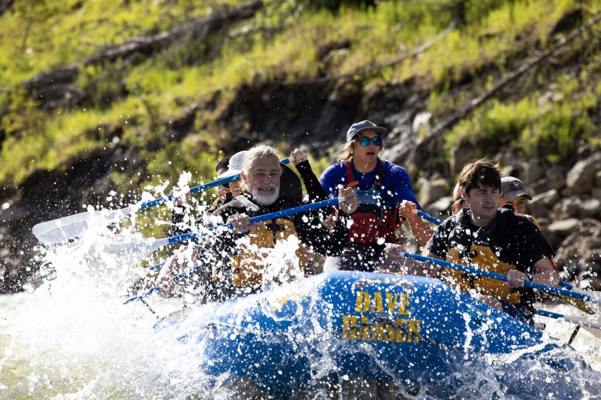 A Dave Hansen Whitewater raft full of guests paddle through a whitewater rapid on the Snake River.