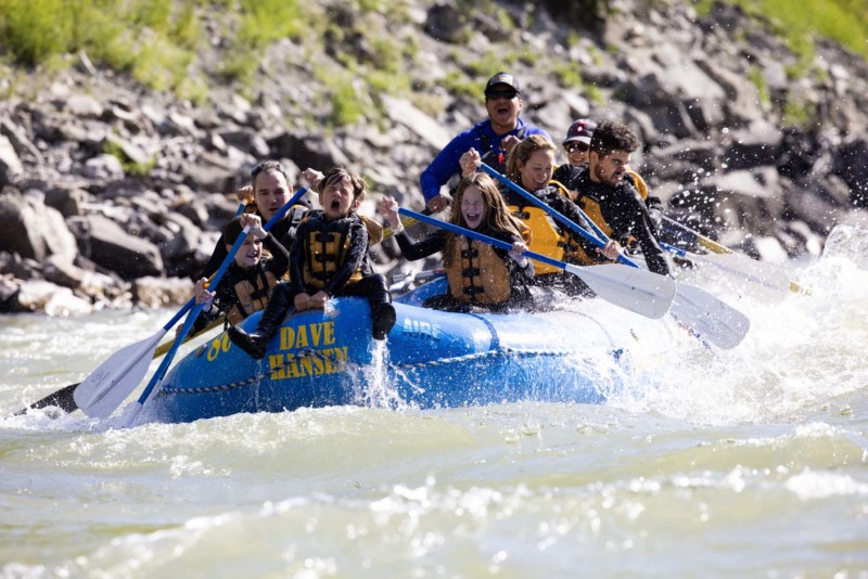 A young boy rides on the front of a blue Dave Hansen Whitewater raft while floating down the Snake River.