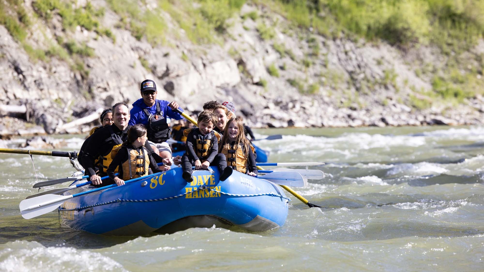 A young boy rides on the front of a blue Dave Hansen Whitewater raft while floating down the Snake River.