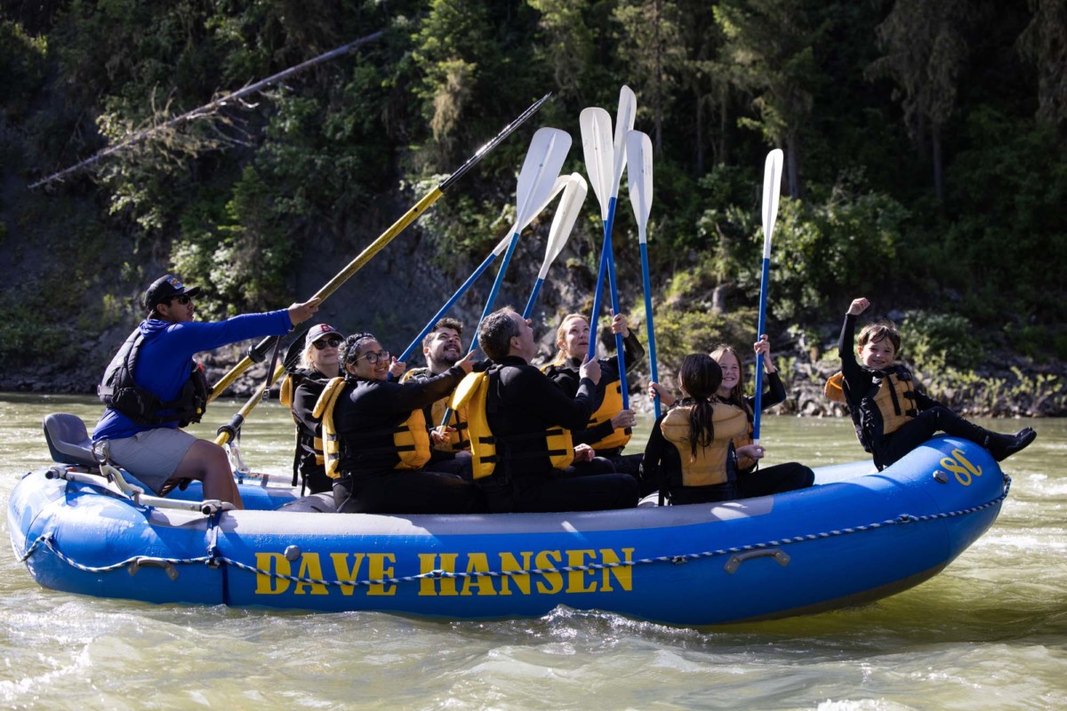 A group of whitewater rafters raise their paddles in a 