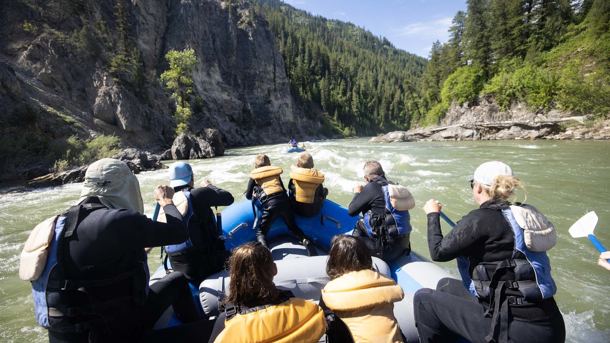 A Dave Hansen Whitewater raft full of guests paddle towards a whitewater rapid on the Snake River.