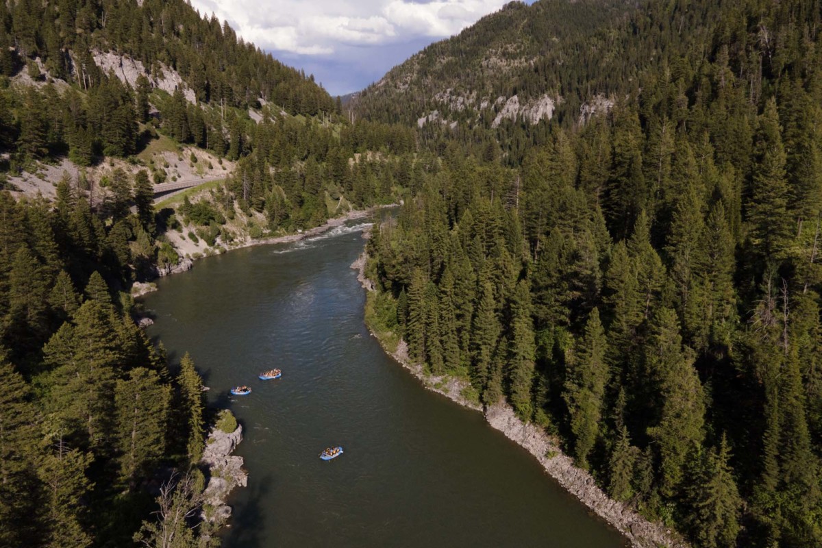 Three blue rafts float down Snake River Canyon in Wyoming.