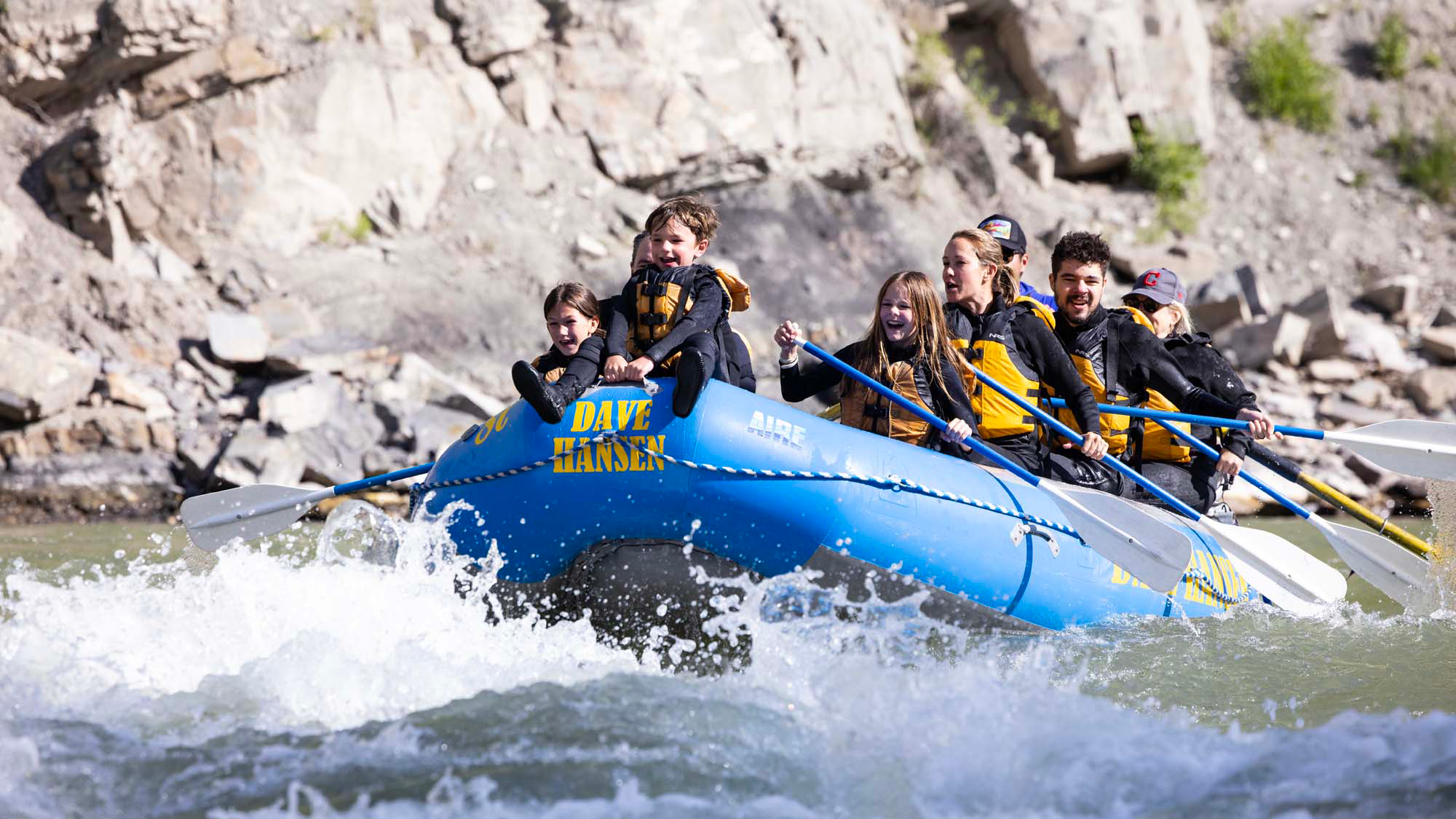 Young boy riding on the front of a blue Dave Hansen Whitewater raft through whitewater rapids on the Snake River.