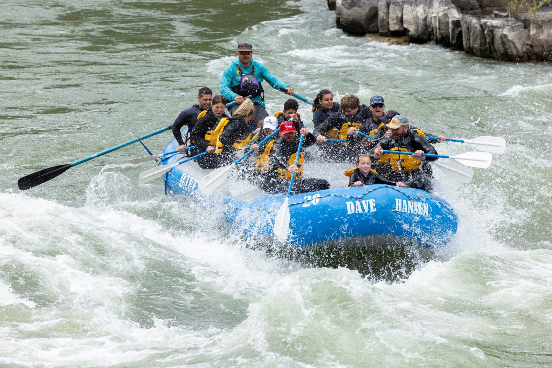 Two Dave Hansen rafts navigating a large whitewater rapid in the Snake River Canyon side by side, with guides steering from the stern and guests paddling hard through the churning water.