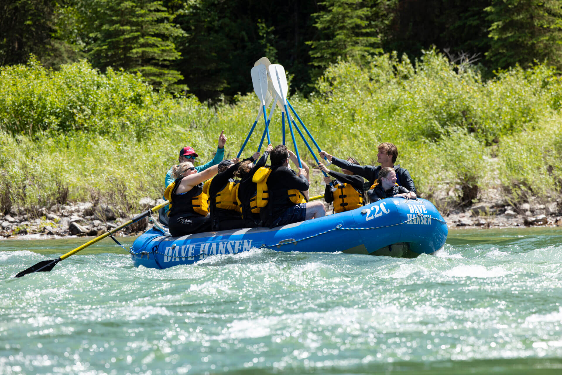 Rafters in a Dave Hansen boat celebrating with a paddle high five on the Snake River